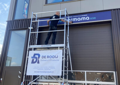 De montage van stickers en een reclamebord met gebruik van een steiger